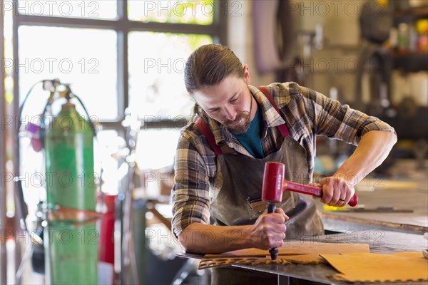 Caucasian man hammering leather