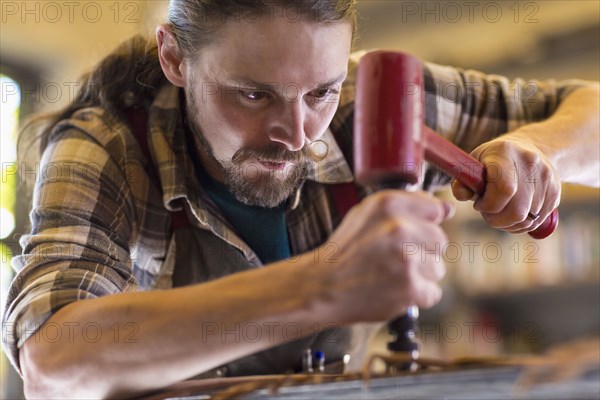 Caucasian man hammering leather