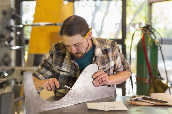 Caucasian man measuring metal with caliper