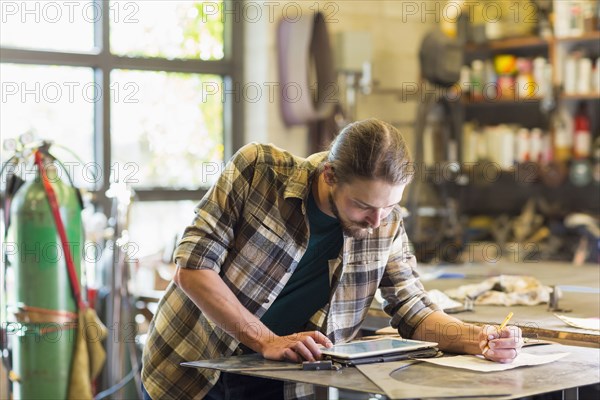 Caucasian man using digital tablet in workshop