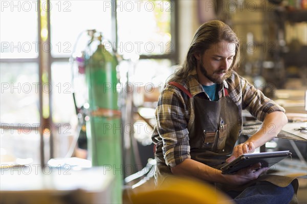 Caucasian man reading a digital tablet in workshop