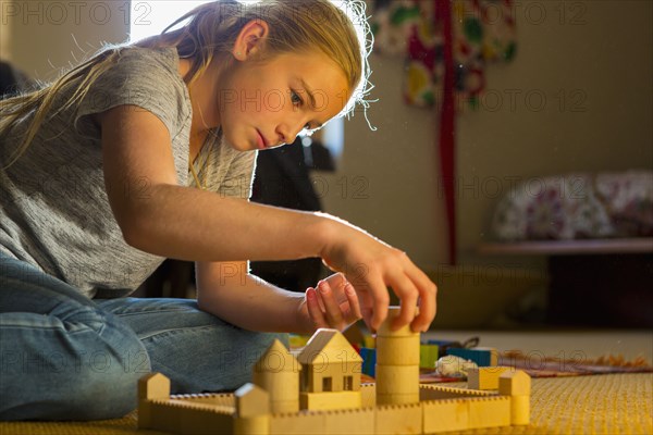 Caucasian girl kneeling on the floor building toys castle