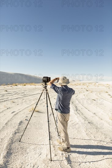 Caucasian photographer with tripod in desert