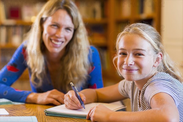 Portrait of Caucasian teacher helping student in library