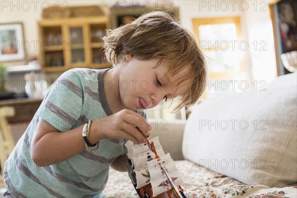 Caucasian boy playing with toy boat on sofa