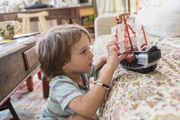 Caucasian boy playing with toy boat on sofa