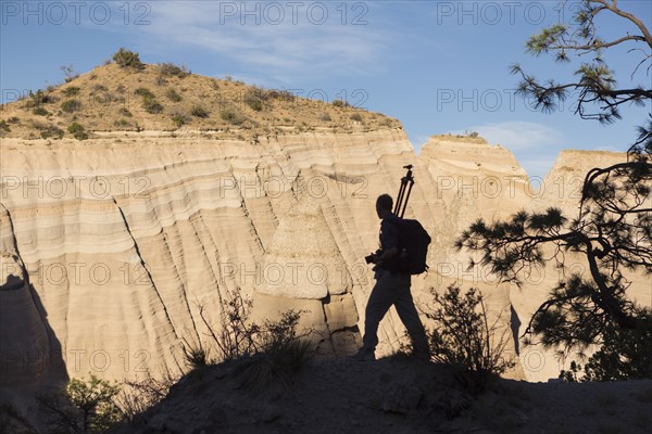 Silhouette of Caucasian man carrying tripod in desert