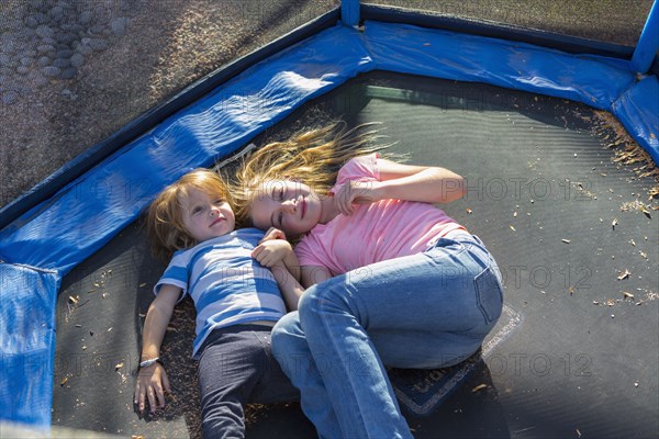 Caucasian brother and sister laying on trampoline