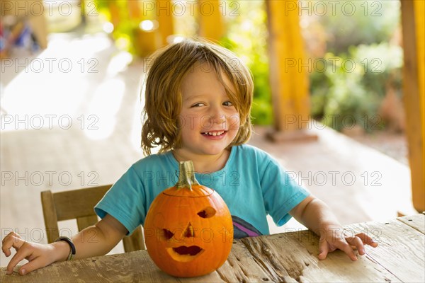 Portrait of smiling Caucasian boy with carved pumpkin