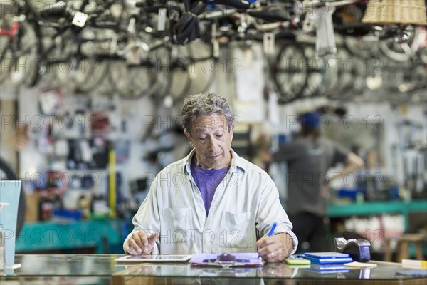Caucasian man in bicycle shop writing on clipboard