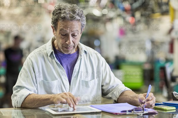 Caucasian man in bicycle shop using digital tablet