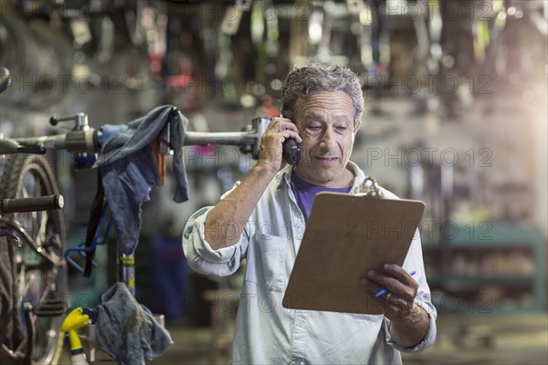 Caucasian man in bicycle shop talking on telephone