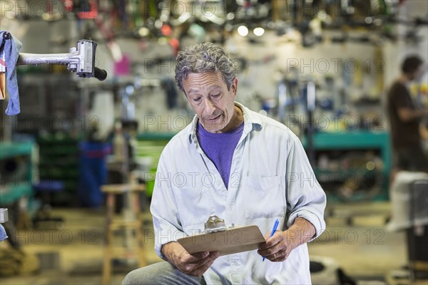 Caucasian man reading clipboard in bicycle shop