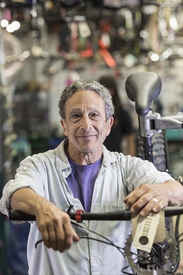 Portrait of smiling Caucasian man leaning on bicycle in shop