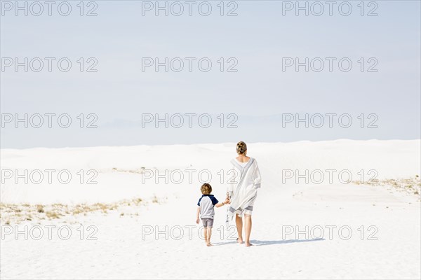Caucasian mother and son walking in sand