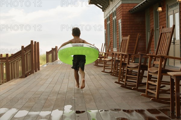Young boy wearing inner tube on wooden deck