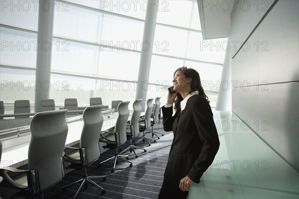 Businesswoman talking on cell phone in conference room