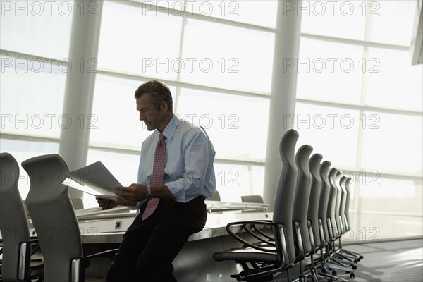 Businessman reading paperwork in conference room