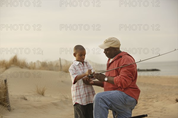 African father and son on beach with fishing gear