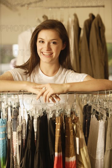 Woman leaning on rack at clothing store