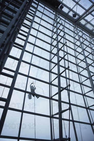 Low angle view of window washer hanging outside building