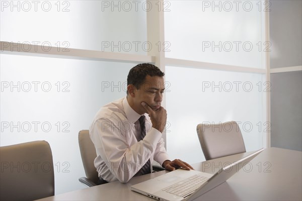 Hispanic businessman looking at laptop