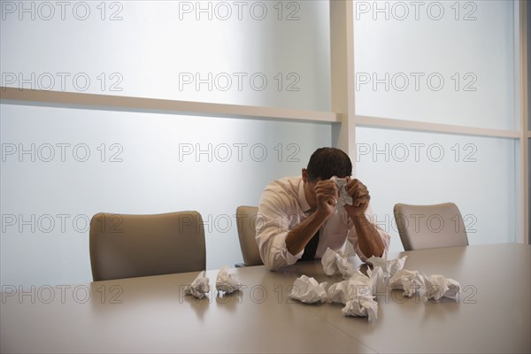 Hispanic businessman next to pile of crumpled paper