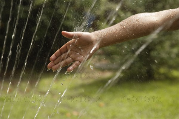 African American boy's hand in sprinkler