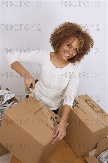 African woman taping moving box