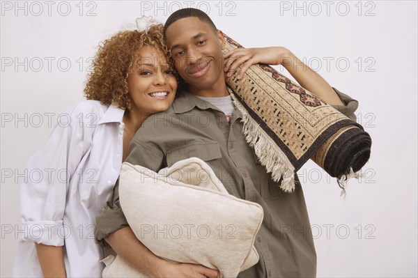 African couple carrying pillows and rug