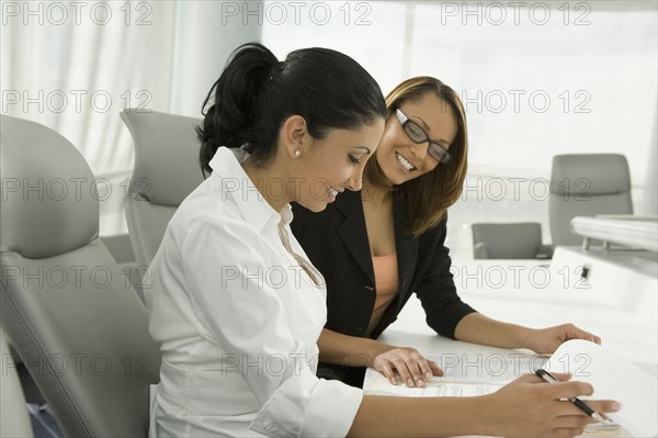 Multi-ethnic businesswomen reviewing paperwork in meeting