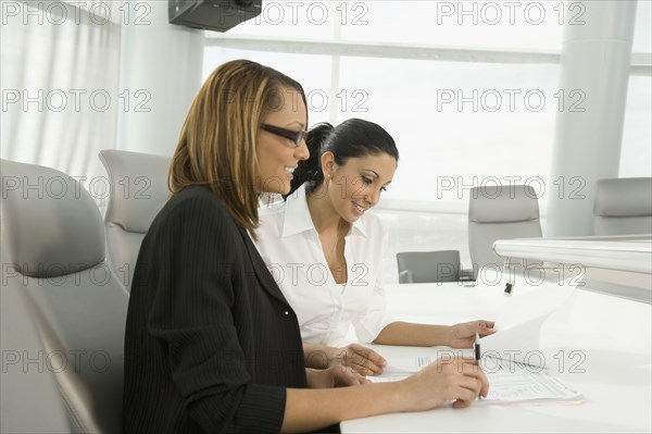 Multi-ethnic businesswomen reviewing paperwork in meeting