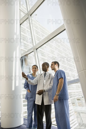 Multi-ethnic doctor and nurses reviewing x-ray by window