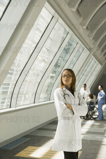 African doctor with arms crossed looking pensive in corridor