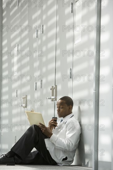 African doctor sitting on floor dictating medical record into recorder