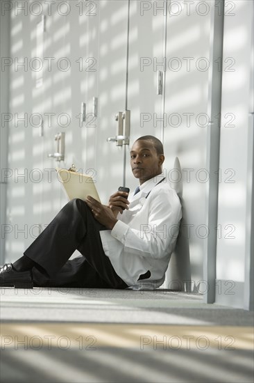 African doctor sitting on floor dictating medical record into recorder