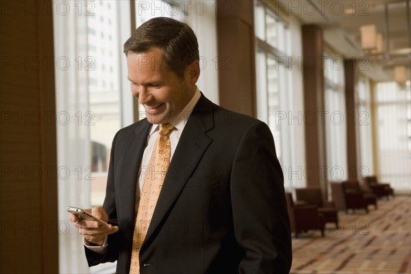 Businessman looking at cell phone in corridor