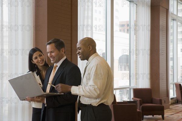 Multi-ethnic business people working on laptop in corridor