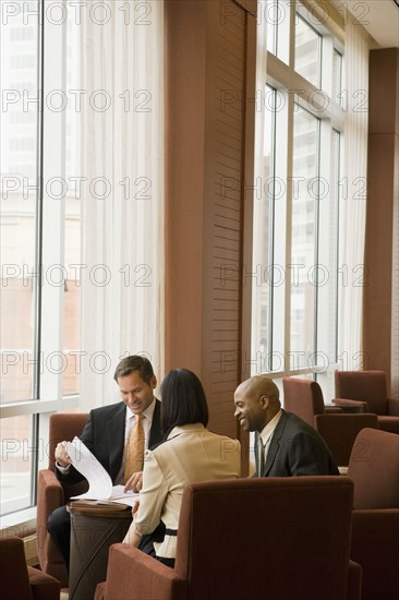 Multi-ethnic business people reviewing paperwork in lobby