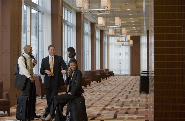 Multi-ethnic business people with suitcases talking in lobby