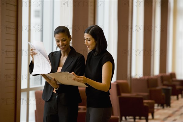 Multi-ethnic businesswoman reviewing paperwork in lobby