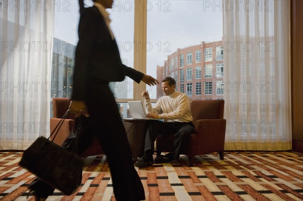 Businessman working on laptop in waiting area near window