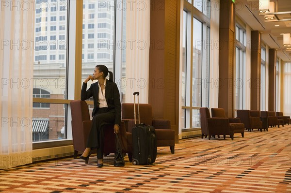 African businesswoman with suitcase looking out window