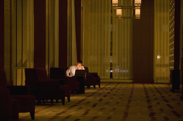 Businessman working on laptop late in lobby