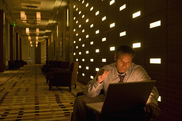 Businessman working on laptop late in lobby