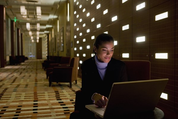 African businesswoman working on laptop late in lobby