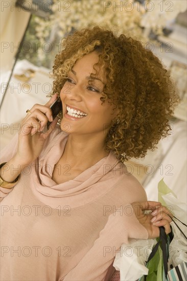 Mixed race woman holding shopping bags talking on cell phone