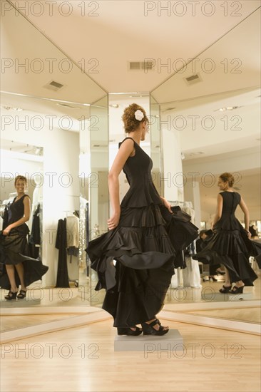 Mixed race woman trying on flamenco dress in shop