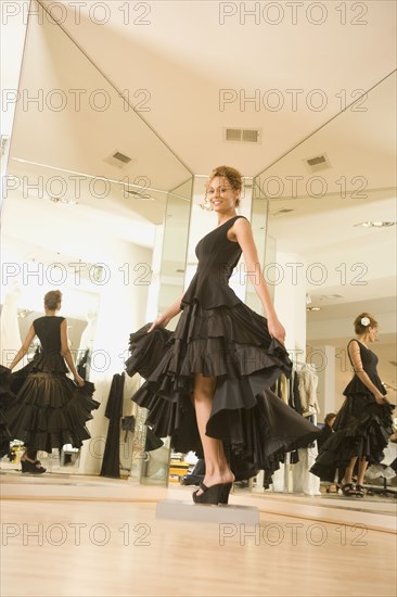 Mixed race woman trying on flamenco dress in shop