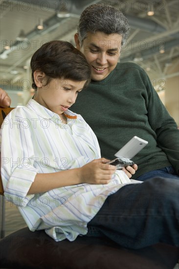 Hispanic father watching son play video game